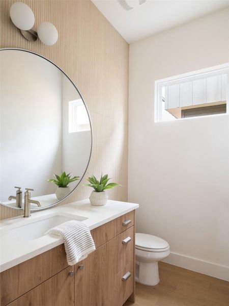 Modern bathroom featuring a wood-finish vanity with a white countertop and integrated sink