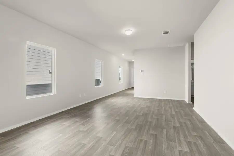 Image of a living room with beige walls, brown wood-look flooring, white trim, and windows Image of a living room with beige walls, brown wood-look flooring, white trim, and windows