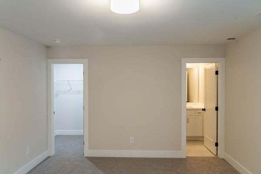 Unfurnished bedroom featuring a closet, light colored carpet, connected bathroom, and a walk in closet Unfurnished bedroom featuring a closet, light colored carpet, connected bathroom, and a walk in closet