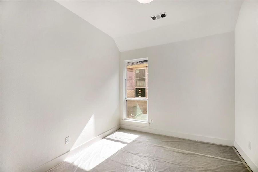 Unfurnished room featuring vaulted ceiling and baseboards