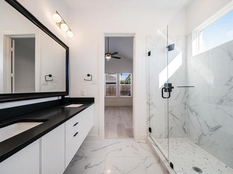 Full bathroom with a marble finish shower, double vanity, light marble finish flooring, and a ceiling fan