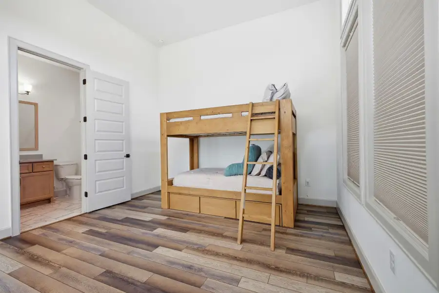 This room features durable plank flooring and large windows with privacy blinds