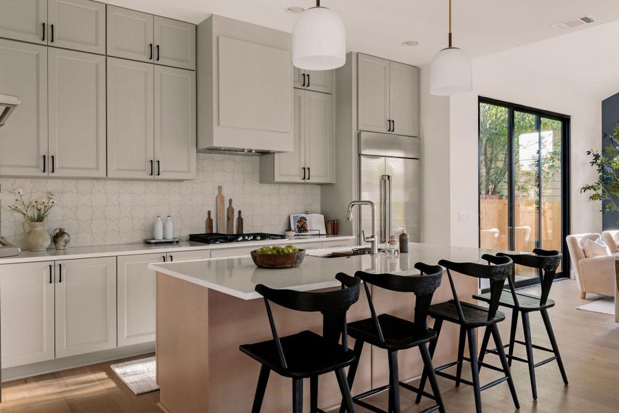Kitchen with backsplash, a kitchen island with sink, a kitchen breakfast bar, hanging light fixtures, and light wood-style floors Kitchen with backsplash, a kitchen island with sink, a kitchen breakfast bar, hanging light fixtures, and light wood-style floors