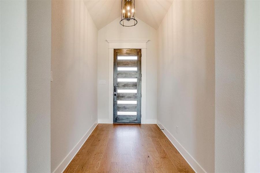 Entrance foyer with lofted ceiling, a chandelier, and hardwood / wood-style flooring