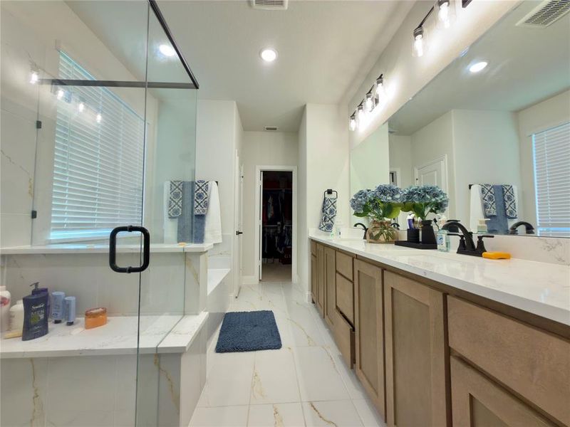 Bathroom with a spacious closet, double vanity, a shower stall, recessed lighting, and light marble finish floors