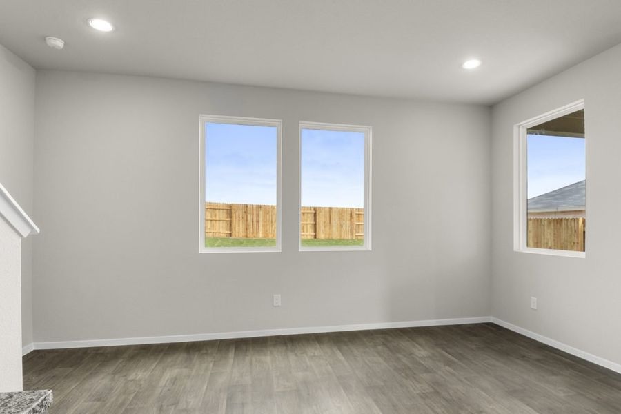 Image of a dining room with light grey walls, dark brown flooring, two windows and white trim