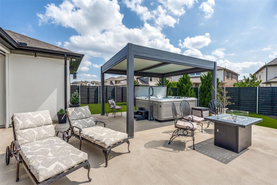 An inviting backyard patio features a modern metal pergola sheltering a private hot tub.