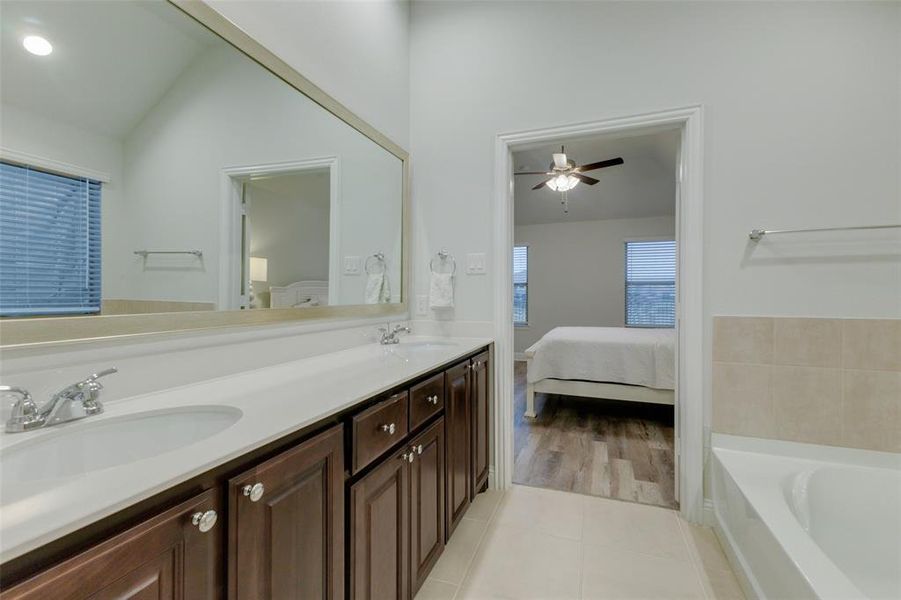 Bathroom with tile patterned floors, vanity, vaulted ceiling, ceiling fan, and a bathing tub