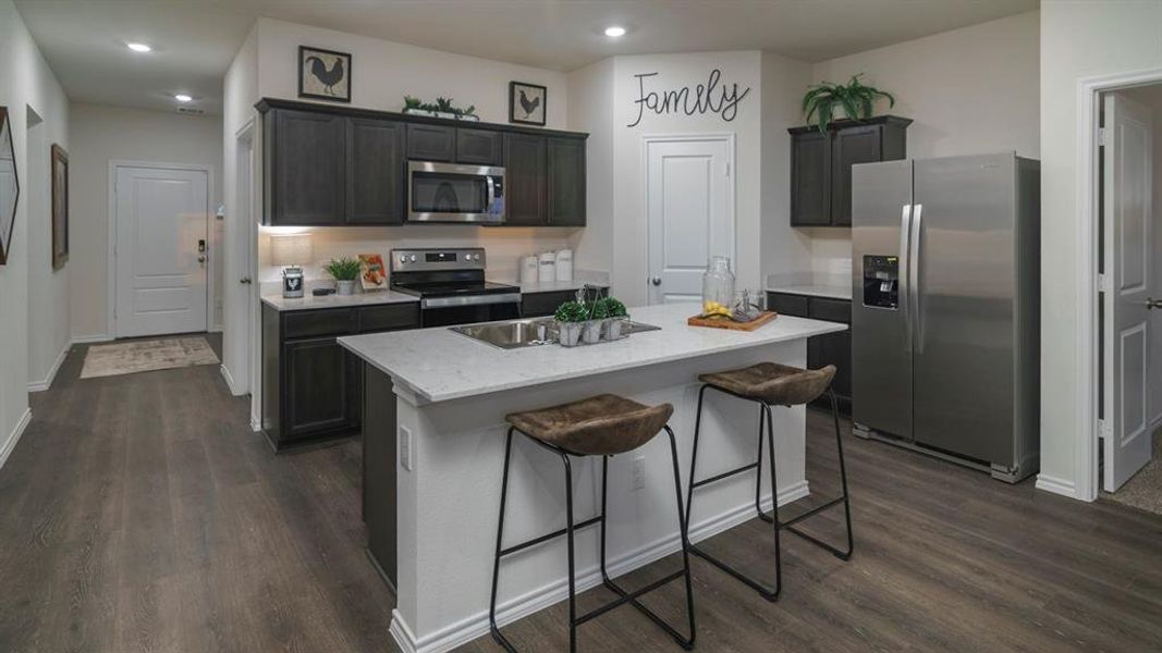 Kitchen featuring stainless steel appliances, a kitchen island with sink, dark wood-style flooring, a kitchen breakfast bar, and recessed lighting