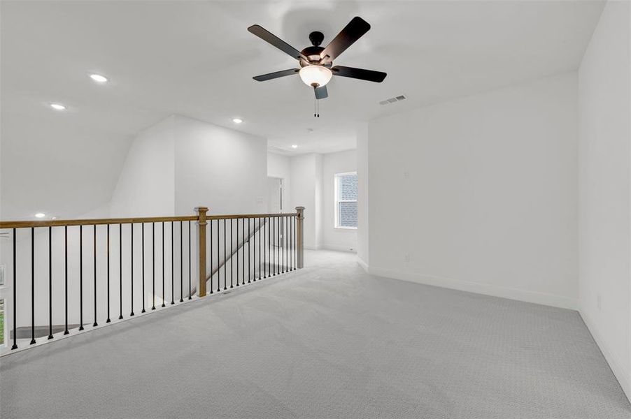 This property features a spacious room with light gray carpeting and white walls, creating a bright and airy atmosphere