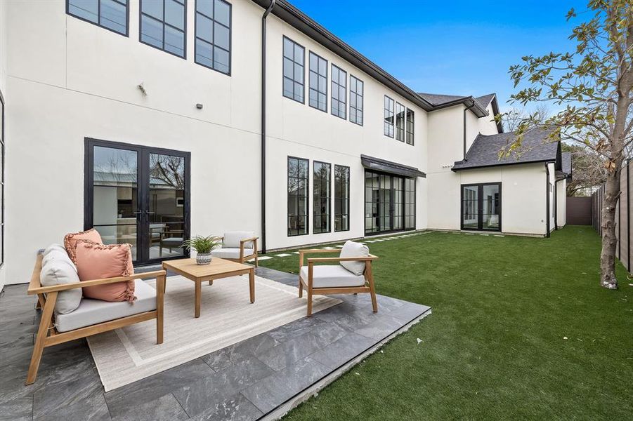 Rear view of property with french doors, stucco siding, a lawn, an outdoor hangout area, and fence