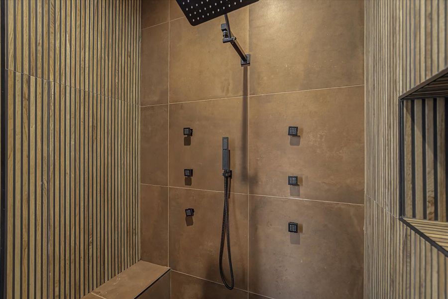 Luxury master bathroom featuring a rainfall shower head, multiple wall-mounted body jets, and a convenient handheld sprayer, all managed by a digital temperature control system.