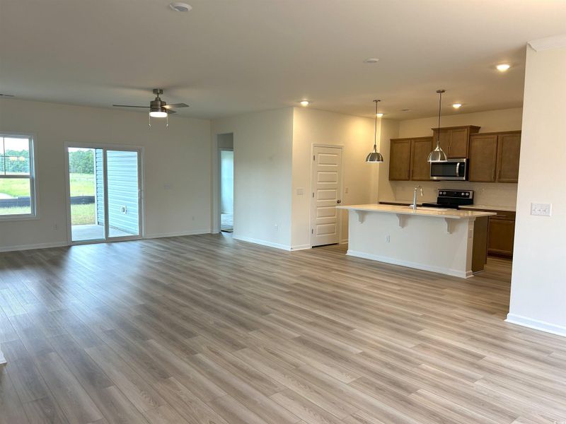 Kitchen featuring open floor plan, a breakfast bar, light wood finished floors, light countertops, and recessed lighting