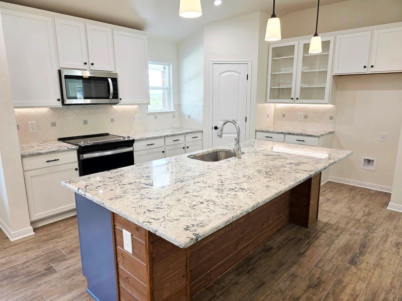 Kitchen with backsplash, range with electric stovetop, glass insert cabinets, a center island with sink, and recessed lighting