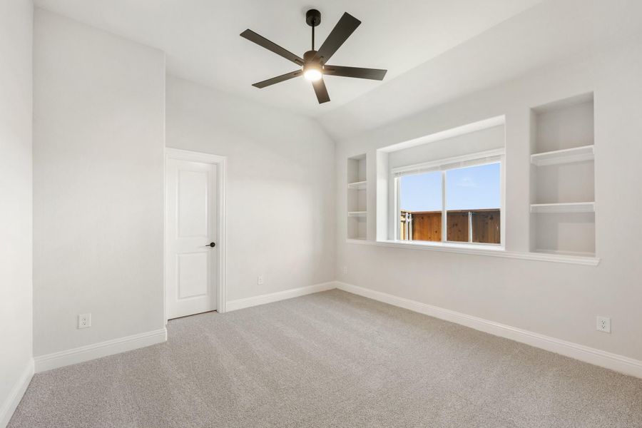 Empty bedroom with vaulted ceiling, ceiling fan, built-in shelves, and carpet flooring Empty bedroom with vaulted ceiling, ceiling fan, built-in shelves, and carpet flooring