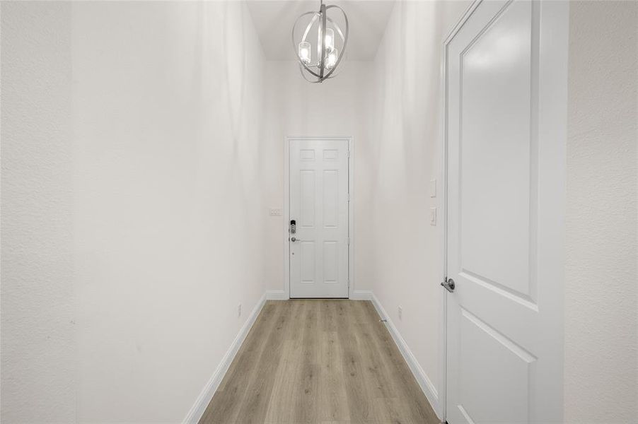 Corridor featuring light wood-type flooring and a chandelier