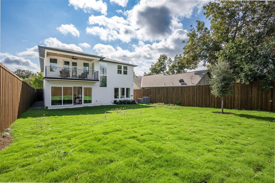 Back of house featuring a fenced backyard, a ceiling fan, stucco siding, a patio, and a balcony Back of house featuring a fenced backyard, a ceiling fan, stucco siding, a patio, and a balcony
