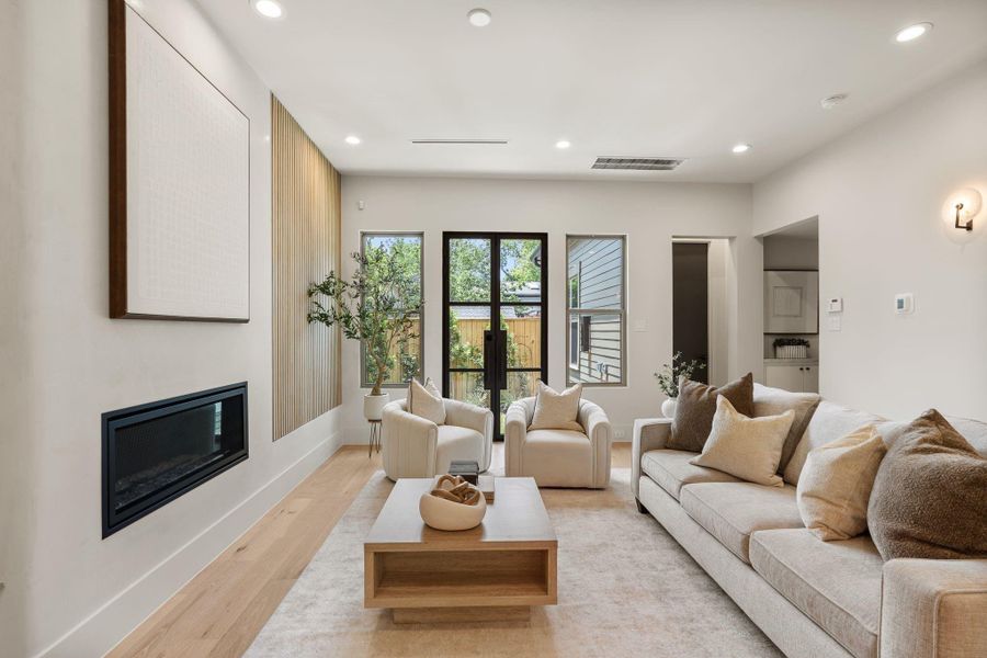 Living room showcasing the retractable wood slat accent wall, sleek rounded plaster fireplace Living room showcasing the retractable wood slat accent wall, sleek rounded plaster fireplace