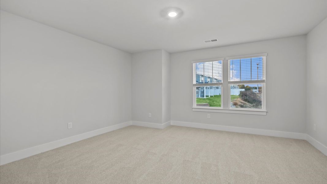 Notable secondary bedroom offering cozy carpeted flooring and a stylish walk-in closet Notable secondary bedroom offering cozy carpeted flooring and a stylish walk-in closet