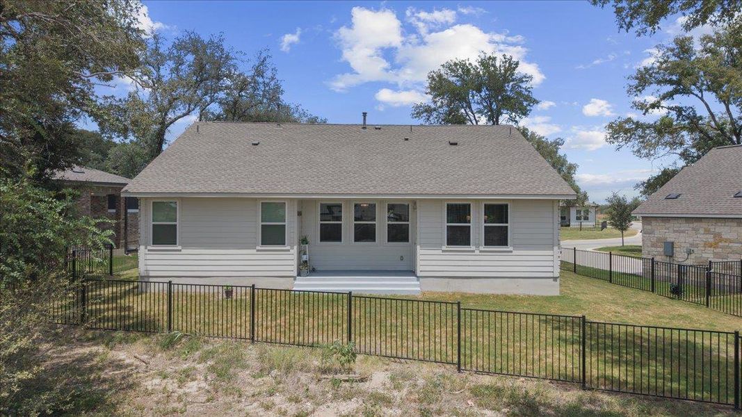 Enclosed metal fencing surrounds a manicured lawn beneath a classic shingle roofline.