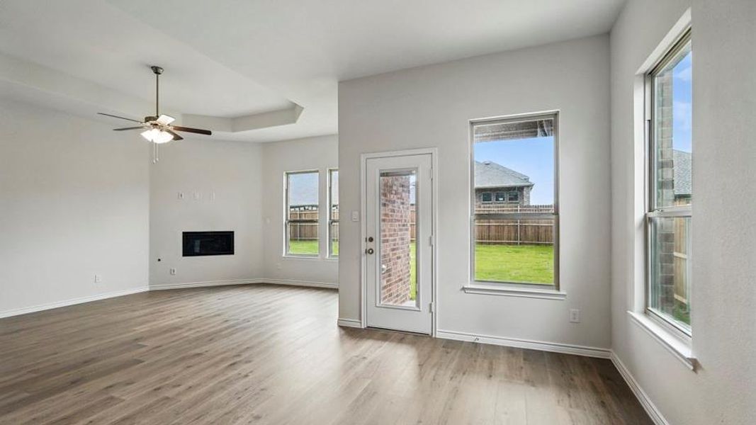 Spacious living area featuring wood-finish flooring, a contemporary ceiling fan, and a built-in electric fireplace