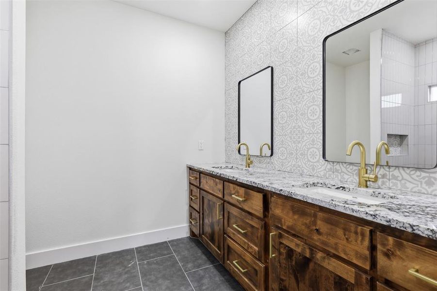 Double vanity featuring wood-finish cabinetry, granite countertops, and two rectangular undermount sinks with gold-tone hardware Double vanity featuring wood-finish cabinetry, granite countertops, and two rectangular undermount sinks with gold-tone hardware