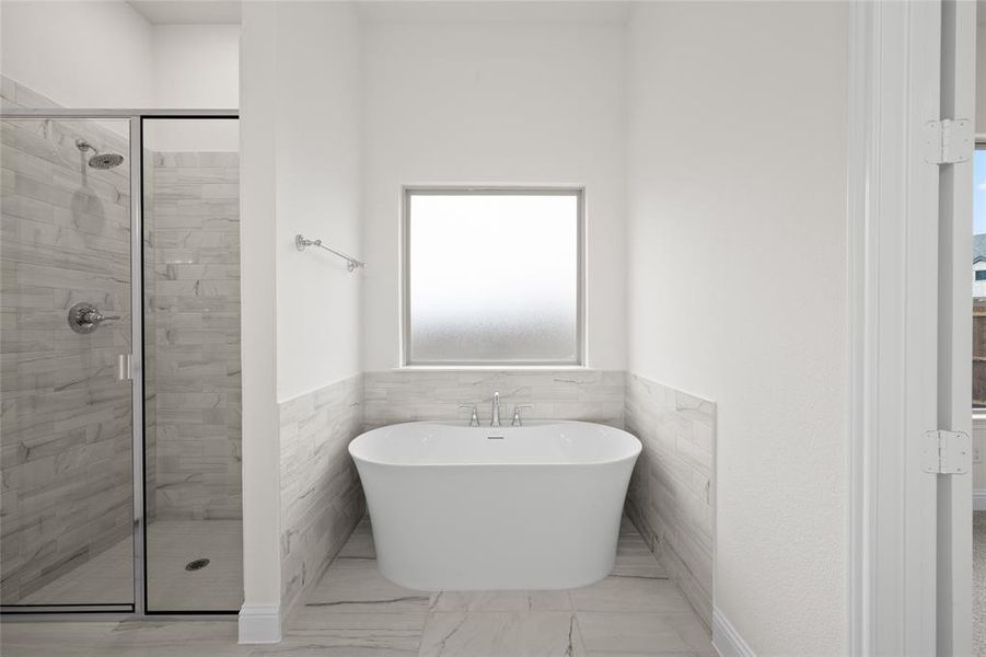 Full bathroom featuring a shower stall, a freestanding bath, a wainscoted wall, and marble finish flooring Full bathroom featuring a shower stall, a freestanding bath, a wainscoted wall, and marble finish flooring