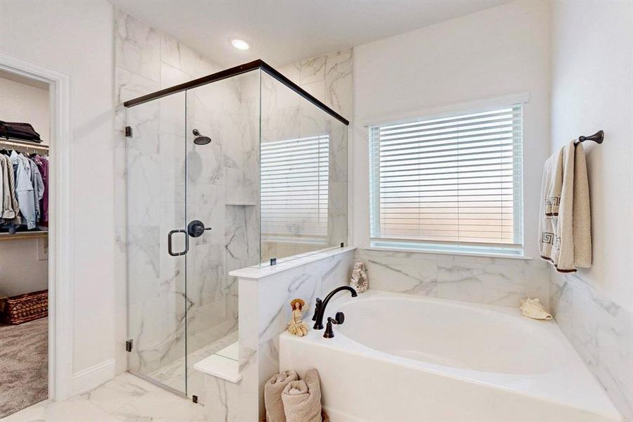Bathroom with a walk in closet, a garden tub, a marble finish shower, marble look tile flooring, and recessed lighting