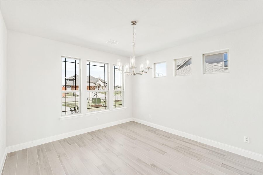 Empty dining room with chandelier, large windows, and light wood-look tile floors Empty dining room with chandelier, large windows, and light wood-look tile floors