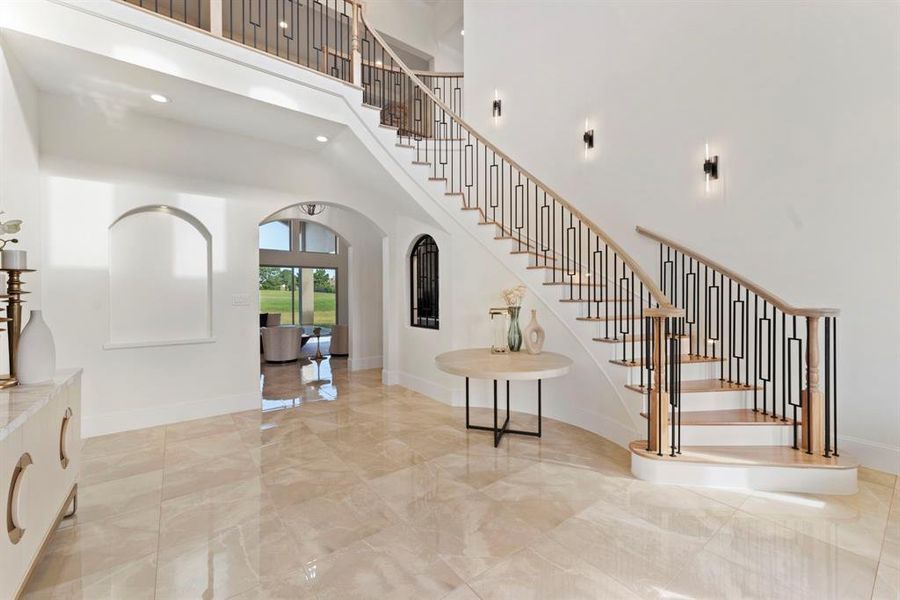 This view of the sweeping staircase with modern metal balusters and wooden handrails, also show the wrought iron opening to your wine cellar.