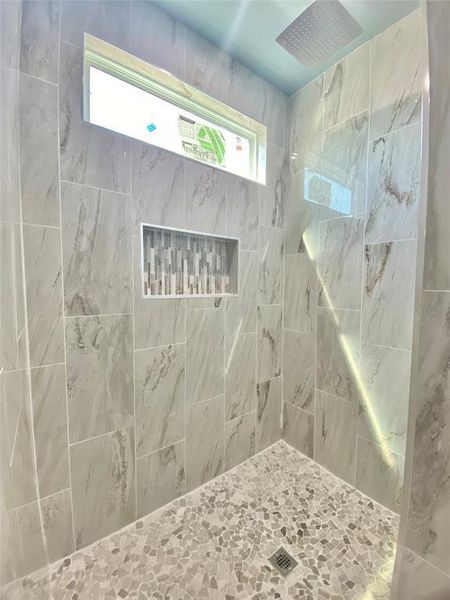 A well-lit shower features tiled walls and a distinctive pebble-tiled floor. A well-lit shower features tiled walls and a distinctive pebble-tiled floor.