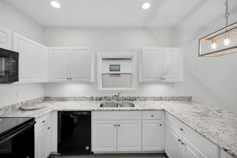 Kitchen featuring recessed lighting, a sink, black appliances, and white cabinetry Kitchen featuring recessed lighting, a sink, black appliances, and white cabinetry