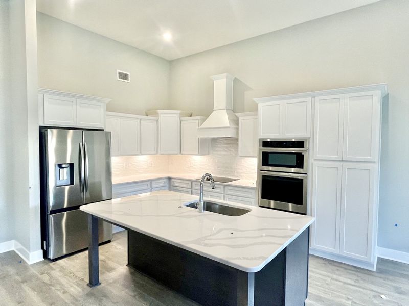 Need a place to entertain and impress? Check out this Gourmet kitchen with ornamental hood, wall oven/microwave, Quartz countertops, undercabinet lights shining down on textured glossy backsplash, upgraded stainless appliances.