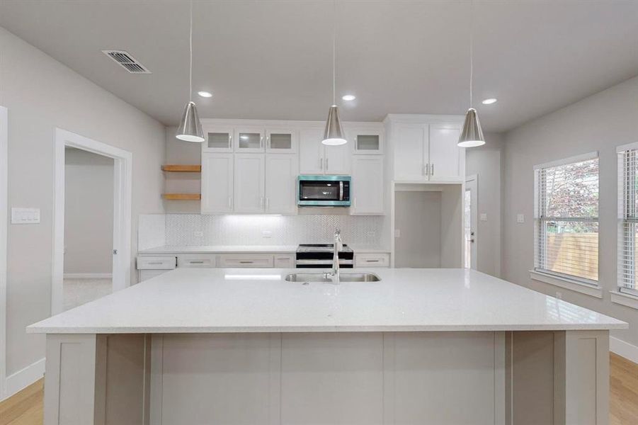 Kitchen featuring a center island with sink, decorative light fixtures, and stainless steel appliances