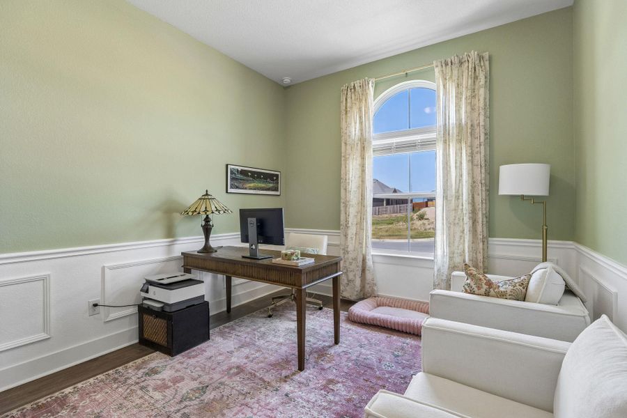 An arched window and classic wainscoting highlight this versatile home office.