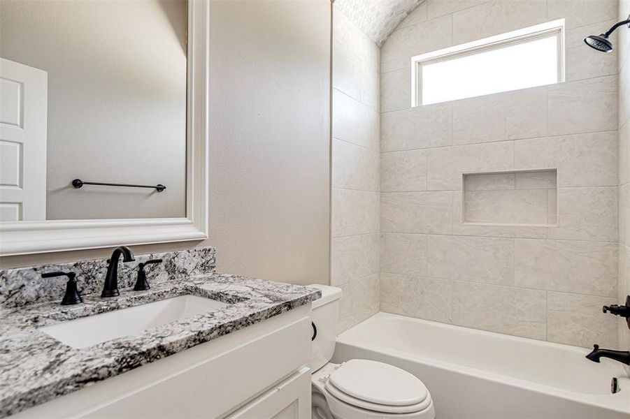 Full bathroom featuring toilet, tiled shower / bath combo, and vanity