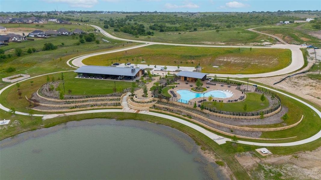Community amenities featuring a curvilinear swimming pool, surrounding lounge seating, and a modern clubhouse with an expansive covered patio
