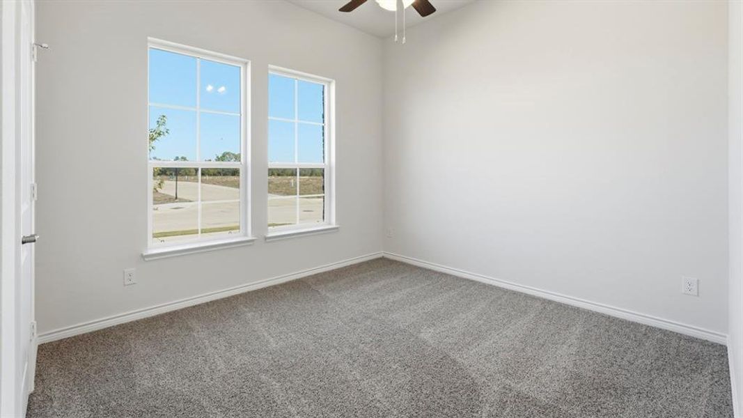 Bright room featuring two large windows, neutral gray carpet, white walls, and a ceiling fan