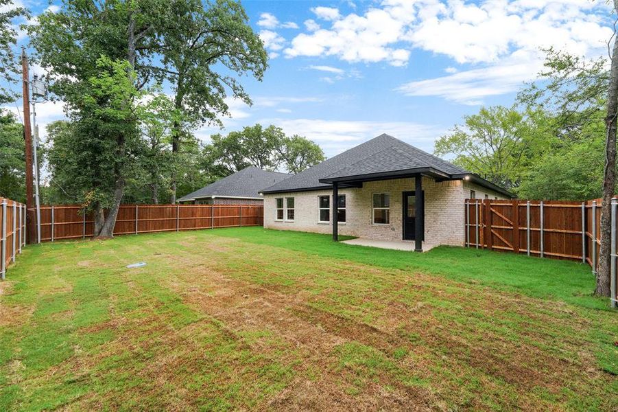 Expansive backyard featuring a new wood privacy fence, a covered patio, and a light brick exterior Expansive backyard featuring a new wood privacy fence, a covered patio, and a light brick exterior