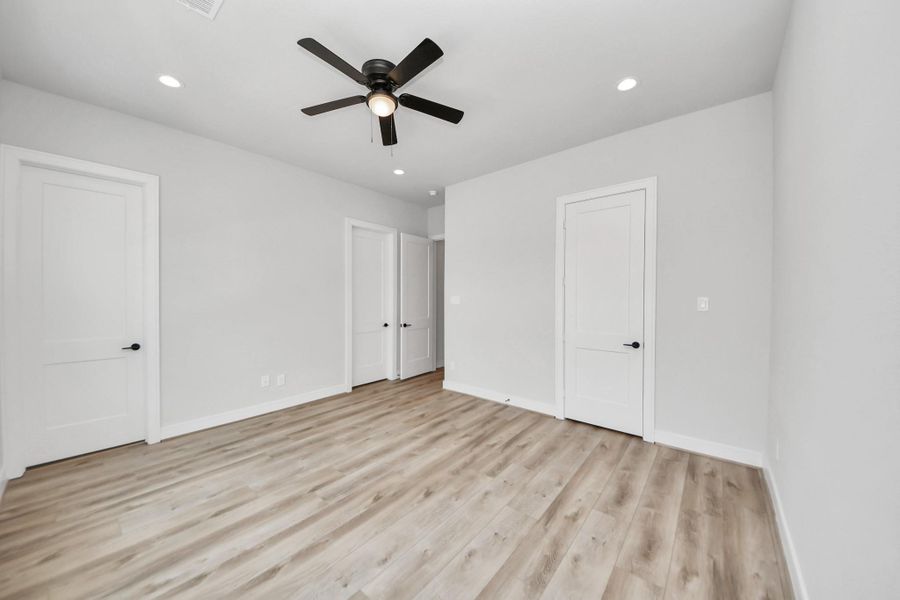 Inviting secondary bedroom with durable vinyl flooring, warm-toned paint, and spacious closets offering plenty of storage. Carpet-free for easy maintenance and a modern touch.
