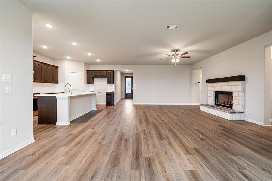 Unfurnished living room featuring light wood-style flooring, a fireplace, a ceiling fan, and recessed lighting