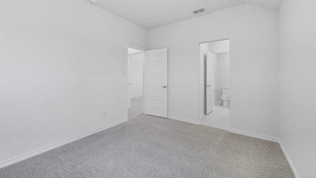 Unfurnished bedroom with carpet floors, ensuite bathroom, and lofted ceiling Unfurnished bedroom with carpet floors, ensuite bathroom, and lofted ceiling