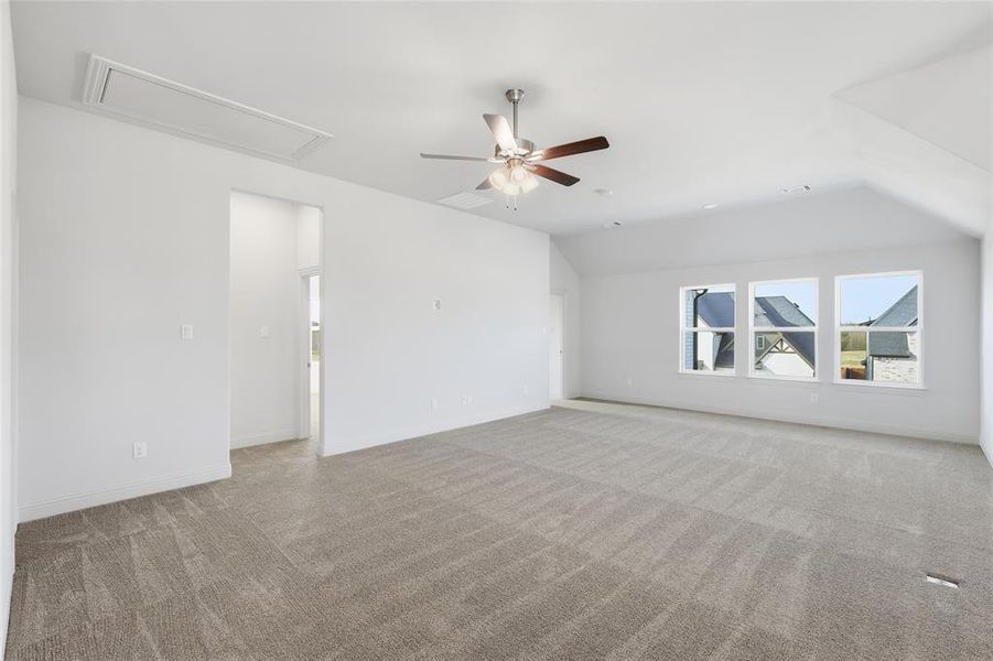 Empty room with light colored carpet, ceiling fan, lofted ceiling, and attic access