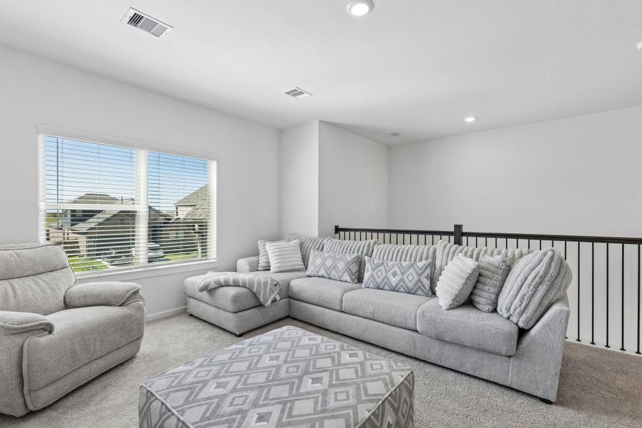 The upstairs gameroom offers a versatile second living area and a clean slate for a media or play space. High windows showcase the home's contemporary architectural style while providing views over the Sunterra community.