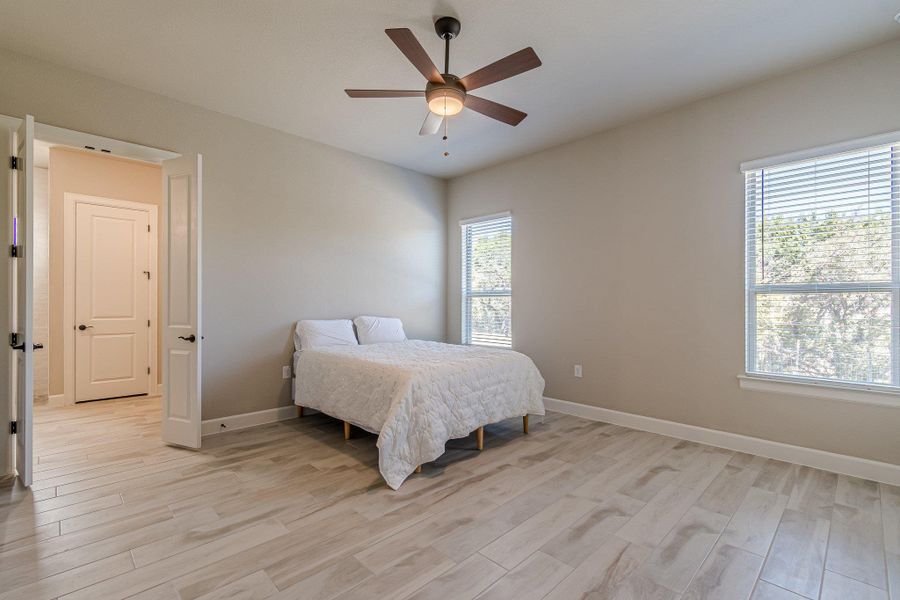 Bedroom featuring a ceiling fan, light wood-style flooring, and baseboards