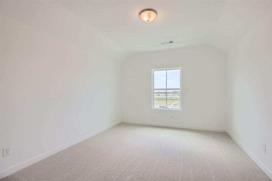 Additional living space with vaulted ceiling, light colored carpet, and baseboards