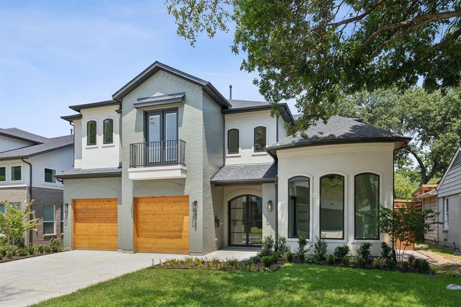 View of front of property with a garage, a front lawn, and a balcony