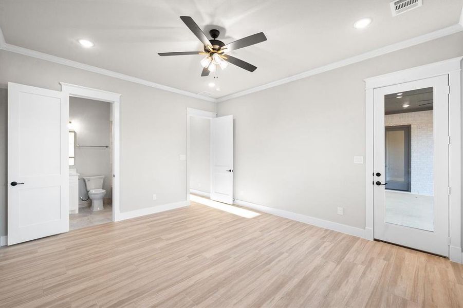 Unfurnished bedroom featuring connected bathroom, light hardwood / wood-style flooring, ceiling fan, and crown molding