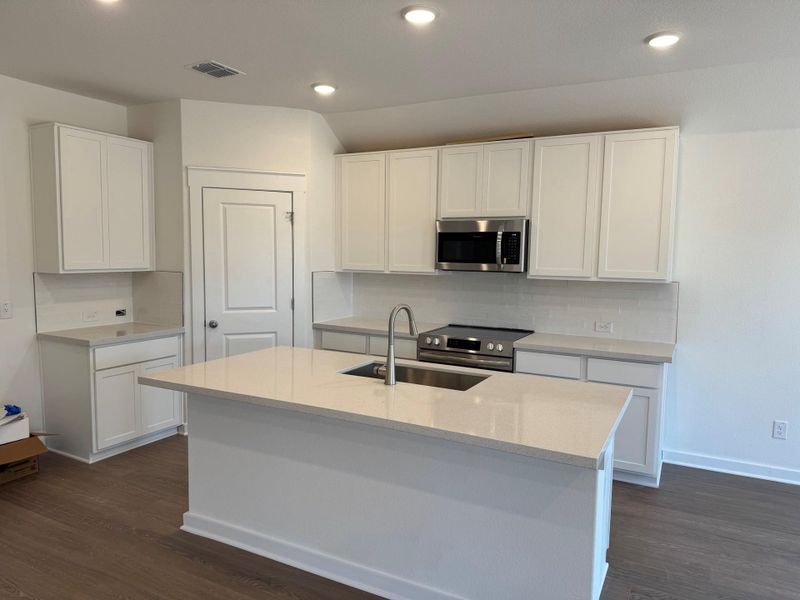 Kitchen featuring appliances with stainless steel finishes, dark wood finished floors, decorative backsplash, white cabinets, and recessed lighting Kitchen featuring appliances with stainless steel finishes, dark wood finished floors, decorative backsplash, white cabinets, and recessed lighting