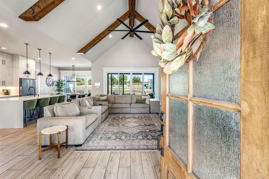 Living room featuring beam ceiling, high vaulted ceiling, recessed lighting, and light wood finished floors